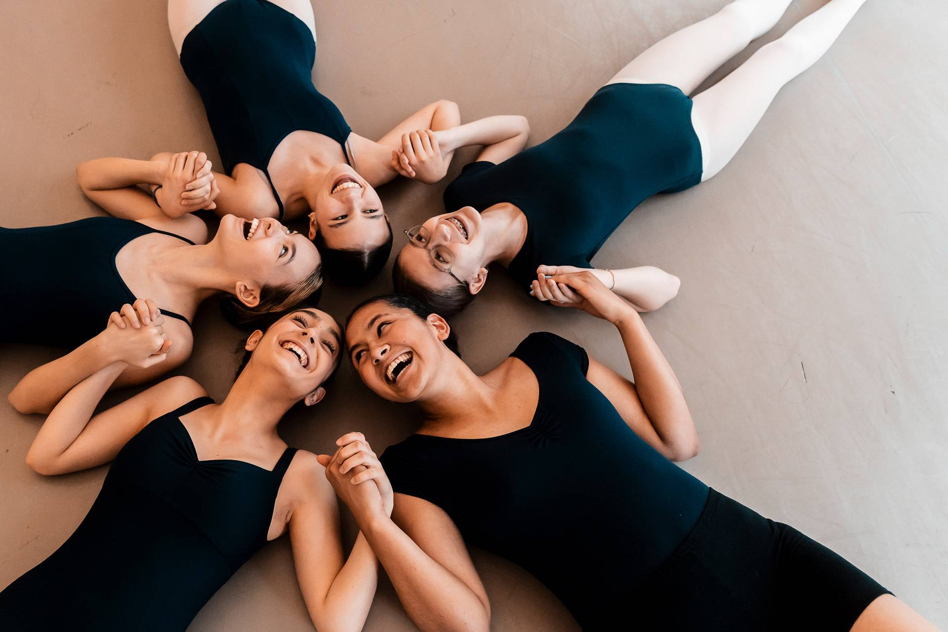 Six ballet dancers at the barre with steps logo above