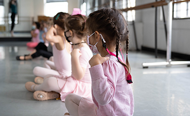 First Steps dance students sitting criss-cross on the floor in pink leotards