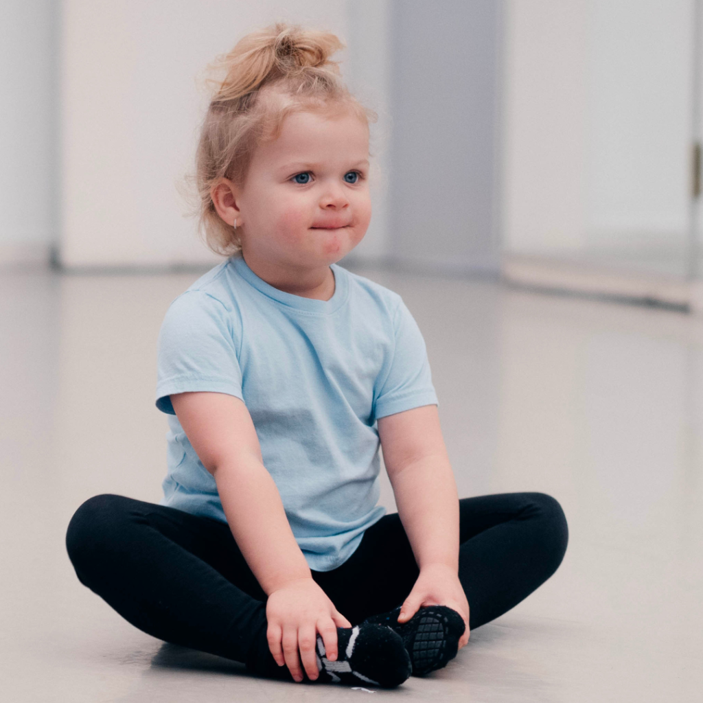 Steps first steps dancer sitting cross legged in the dance studio with a look of serious concentration on their fac