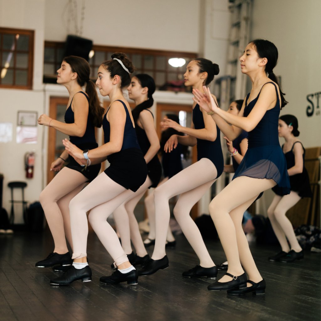 Eight tap dancers in Steps Academy dance class - seen from the slde focusing on thier work