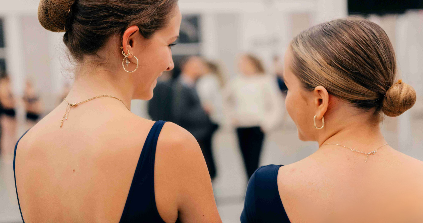 Two academy dancers up close from behind discussing dance