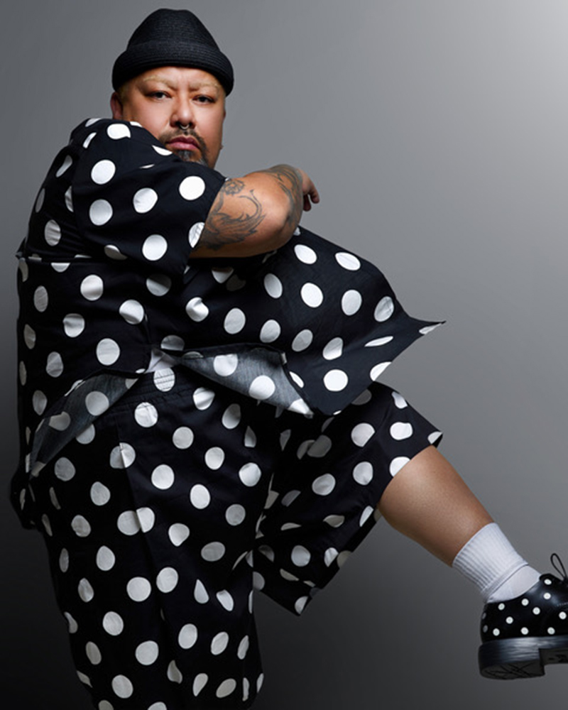 Mike Esperanza in white polka dots on black, seated wiht his head turned to the carmera