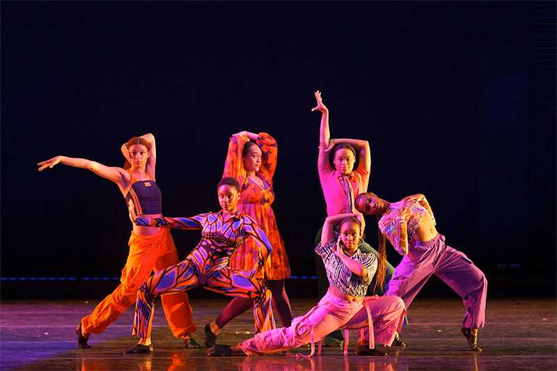 SMU Meadows School of Art dancers - in colorful outfits performing on a simple beautifully lit stage