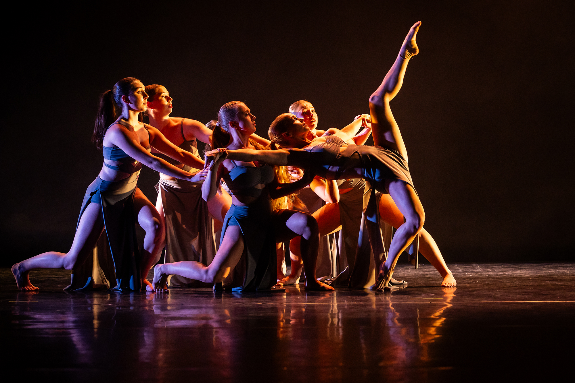 University at Buffalo student dancers in a large group performing on a dramatically light stage