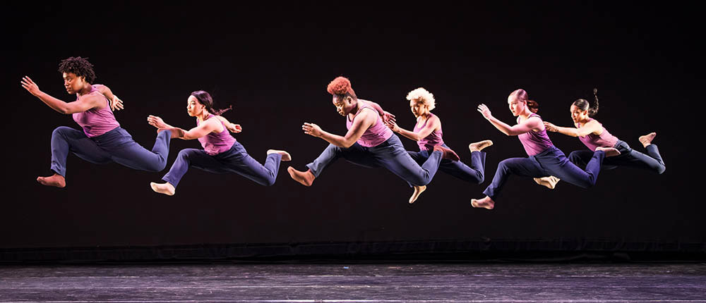 Point Park University Dance students performing on stage - gropu of women leaping to stage left